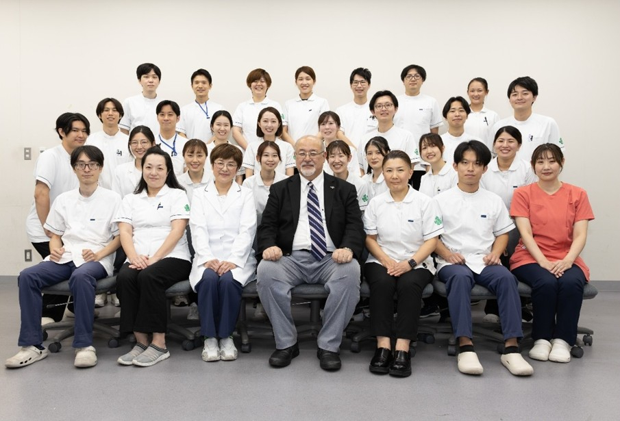 矯正歯科スタッフの集合写真。科長の川元氏を中心とし、多くのスタッフが集っている。